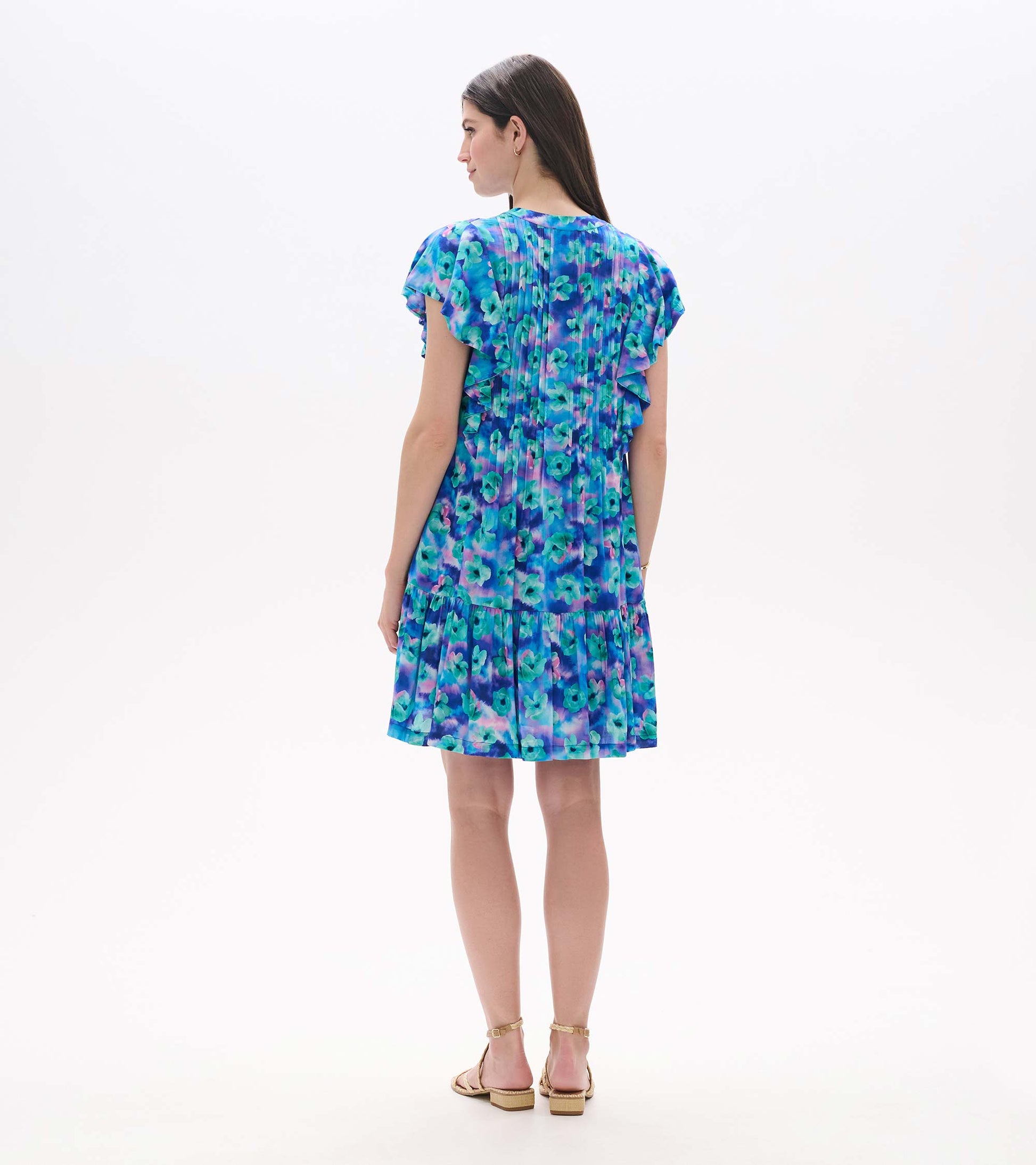 Back view of floating flowers pintuck dress with blue and purple floral print, flutter sleeves, and ruffled hem