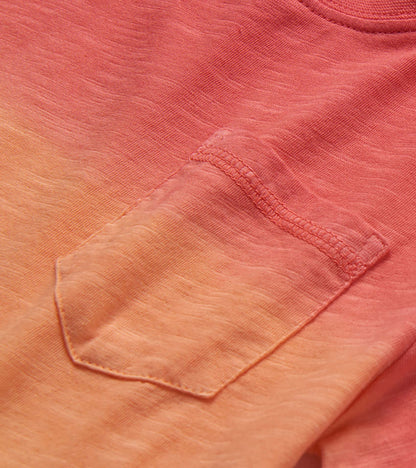 Close-up of a coral and peach gradient knit T-shirt pocket with stitched detail