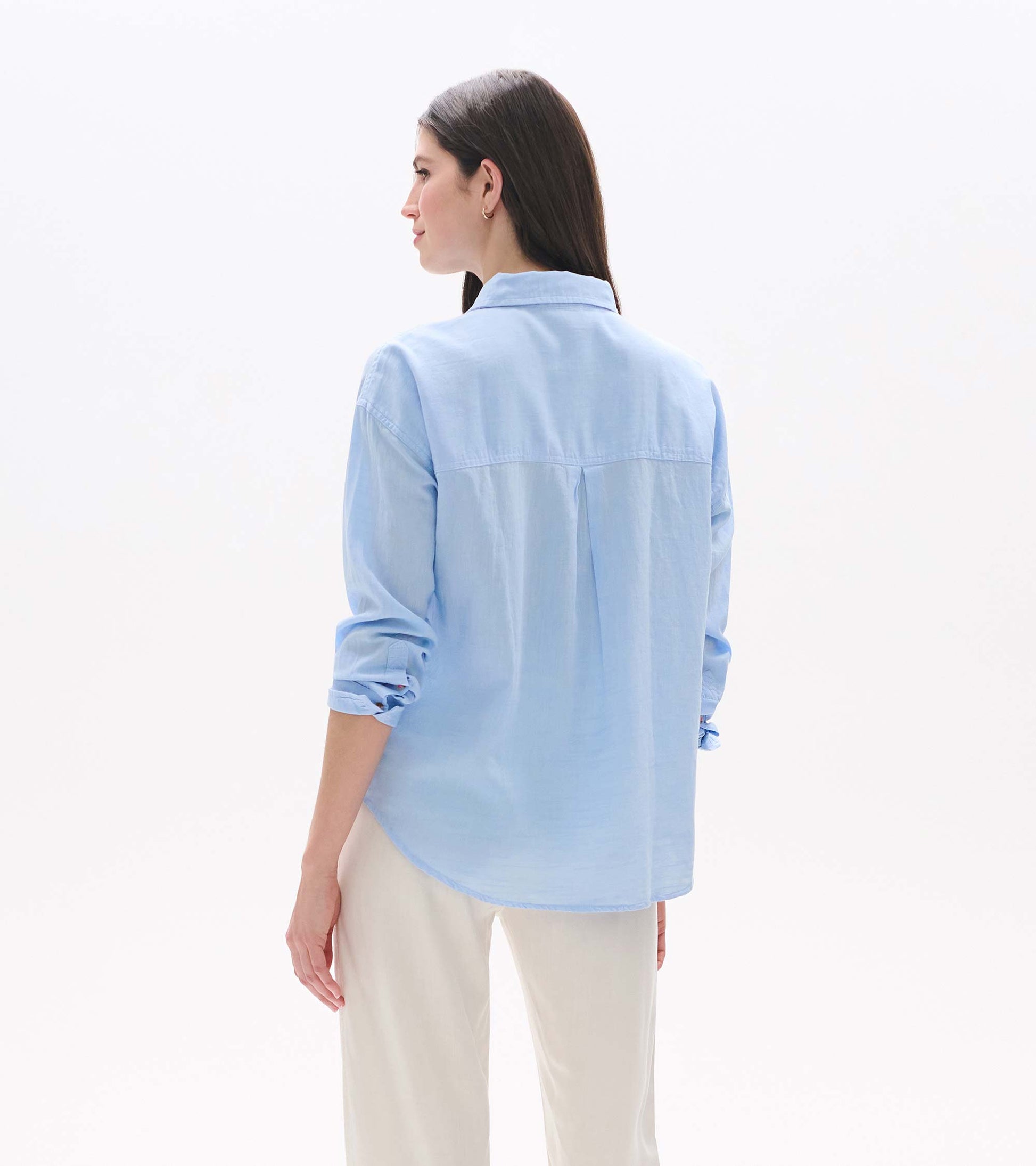 Light blue chambray button-down shirt shown from the back, with rolled sleeves and a relaxed fit