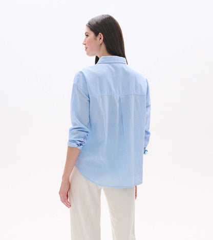 Light blue chambray button-down shirt shown from the back, with rolled sleeves and a relaxed fit