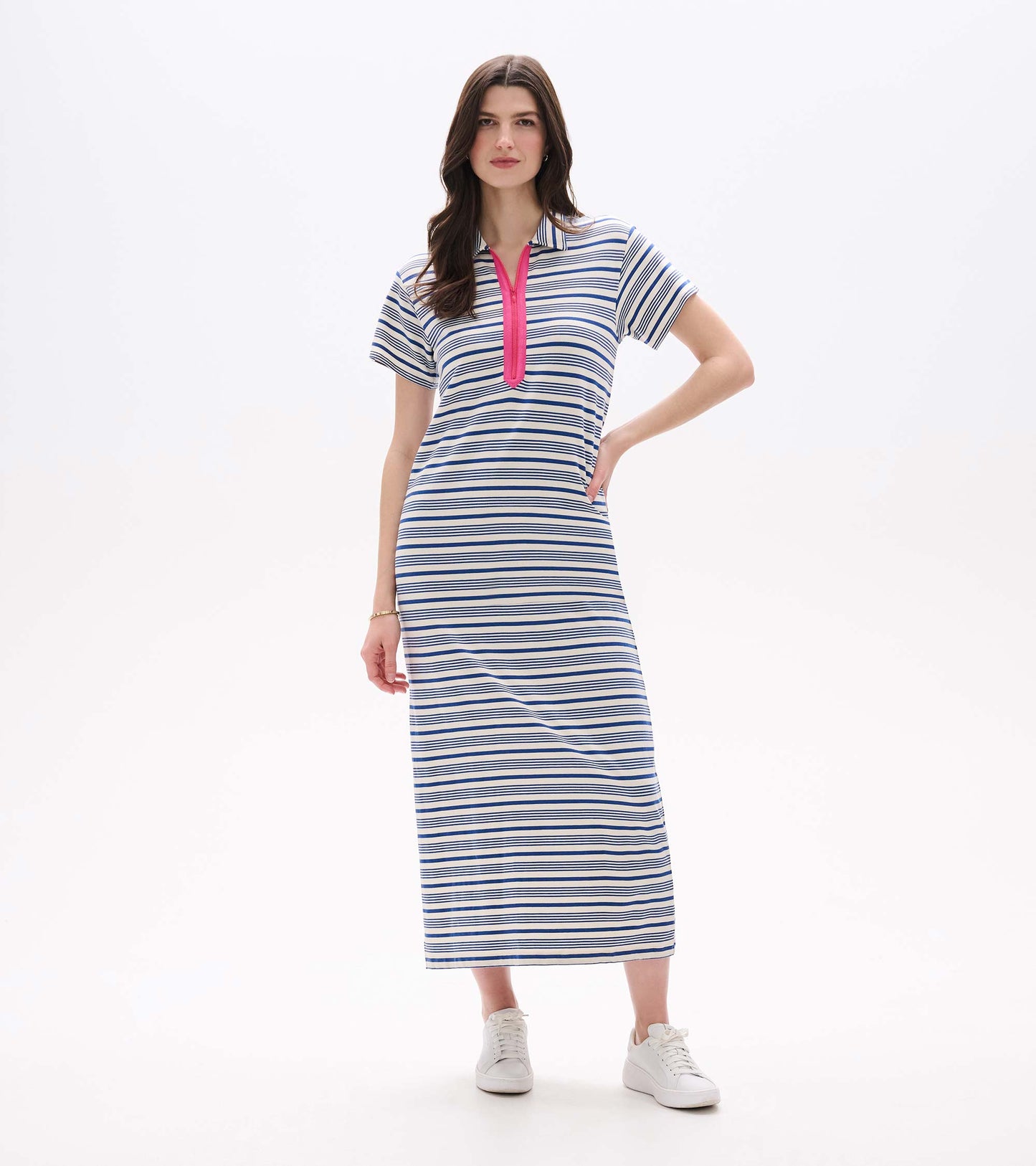 Front view of a white maxi dress with blue stripes, short sleeves, and a pink zip neckline, worn with sneakers