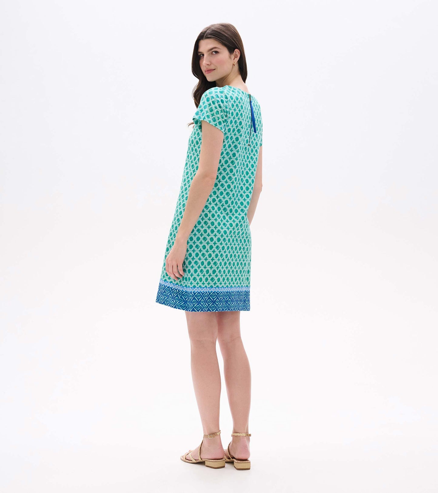 Back angled view of green and white medallion print tee dress with blue zipper detail and border hem