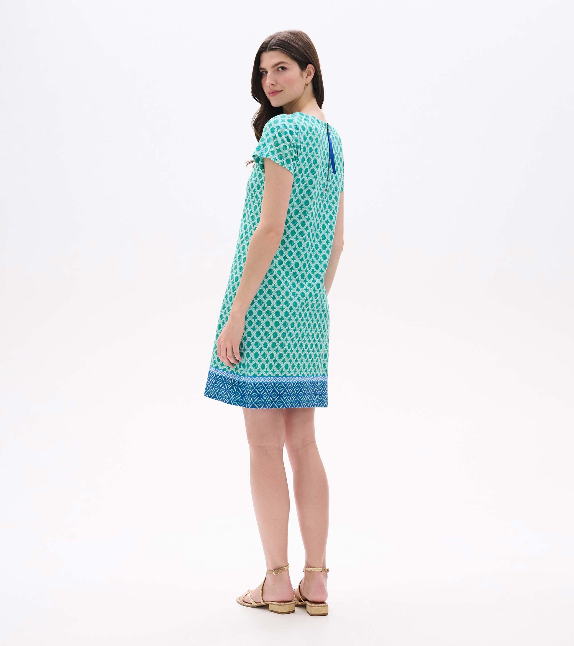 Back angled view of green and white medallion print tee dress with blue zipper detail and border hem