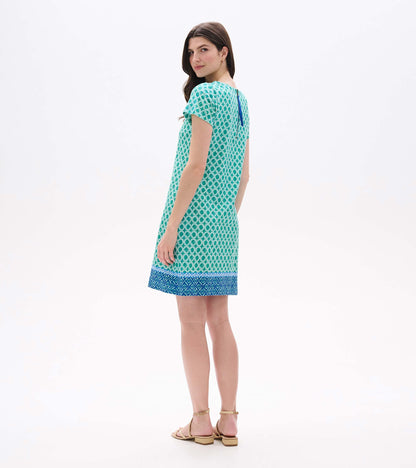 Back angled view of green and white medallion print tee dress with blue zipper detail and border hem