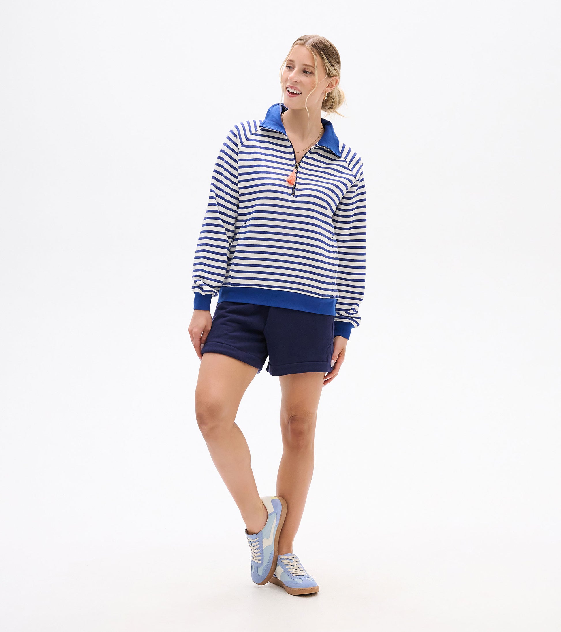 Front view of blue and white striped mock neck pullover worn with navy shorts