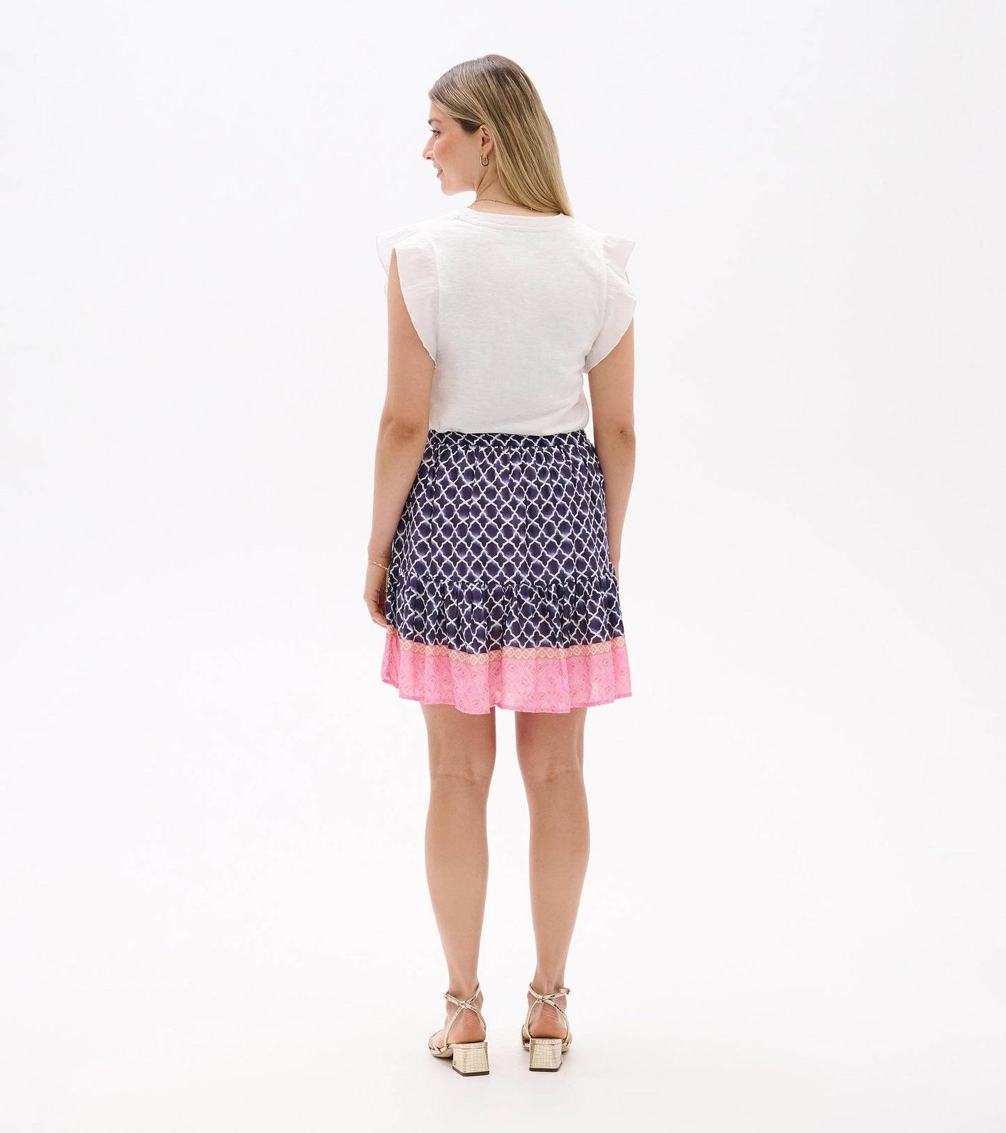 Back view of a navy and pink tiered flounce skirt with white medallion print, worn by a model