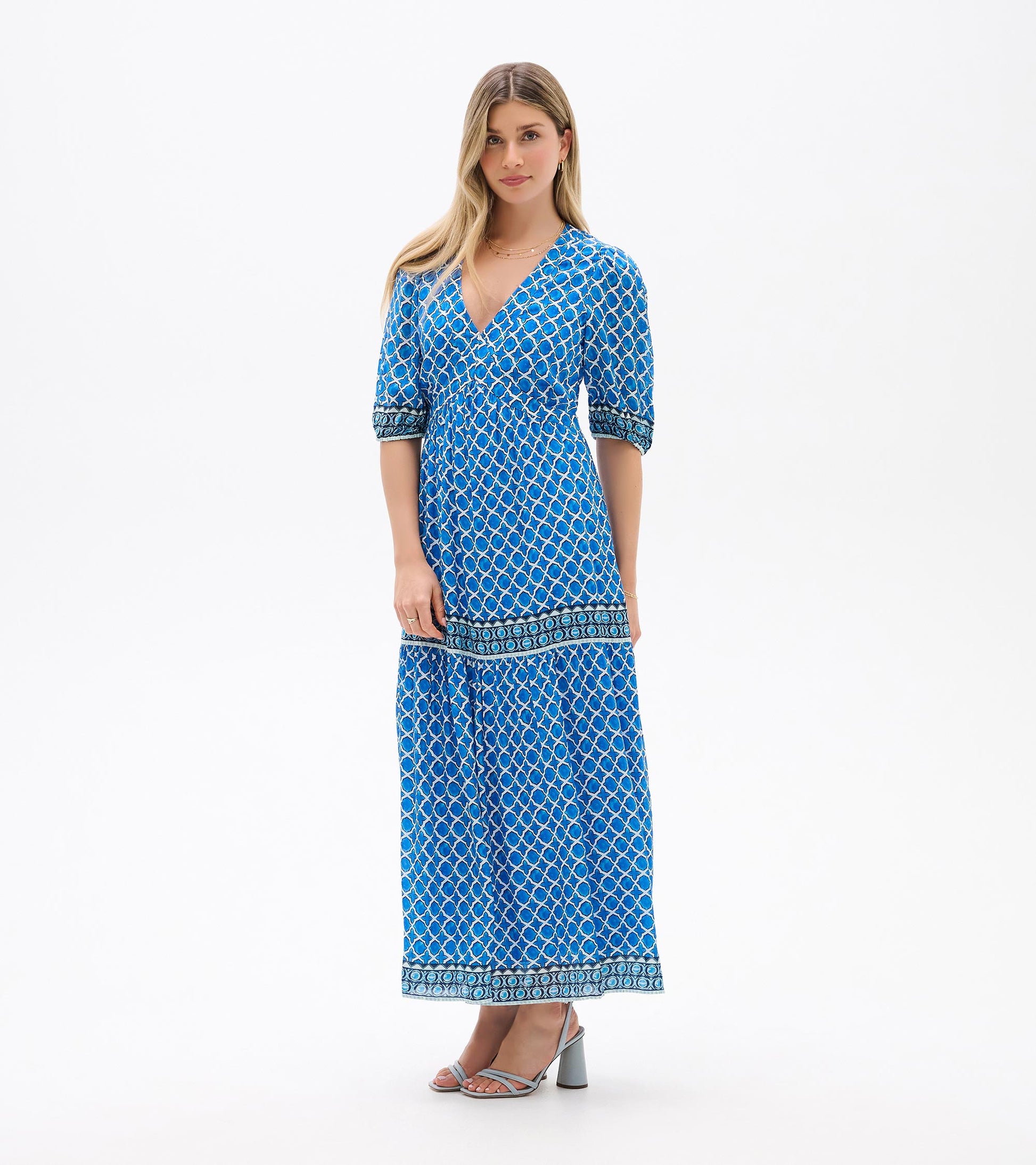 Blue patterned midi dress with V-neck, short sleeves, and tiered skirt, shown on a model.