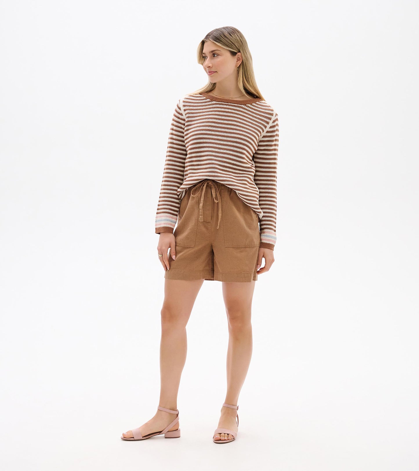 Front view of neutral striped pointelle sweater with long sleeves and brown neckline trim