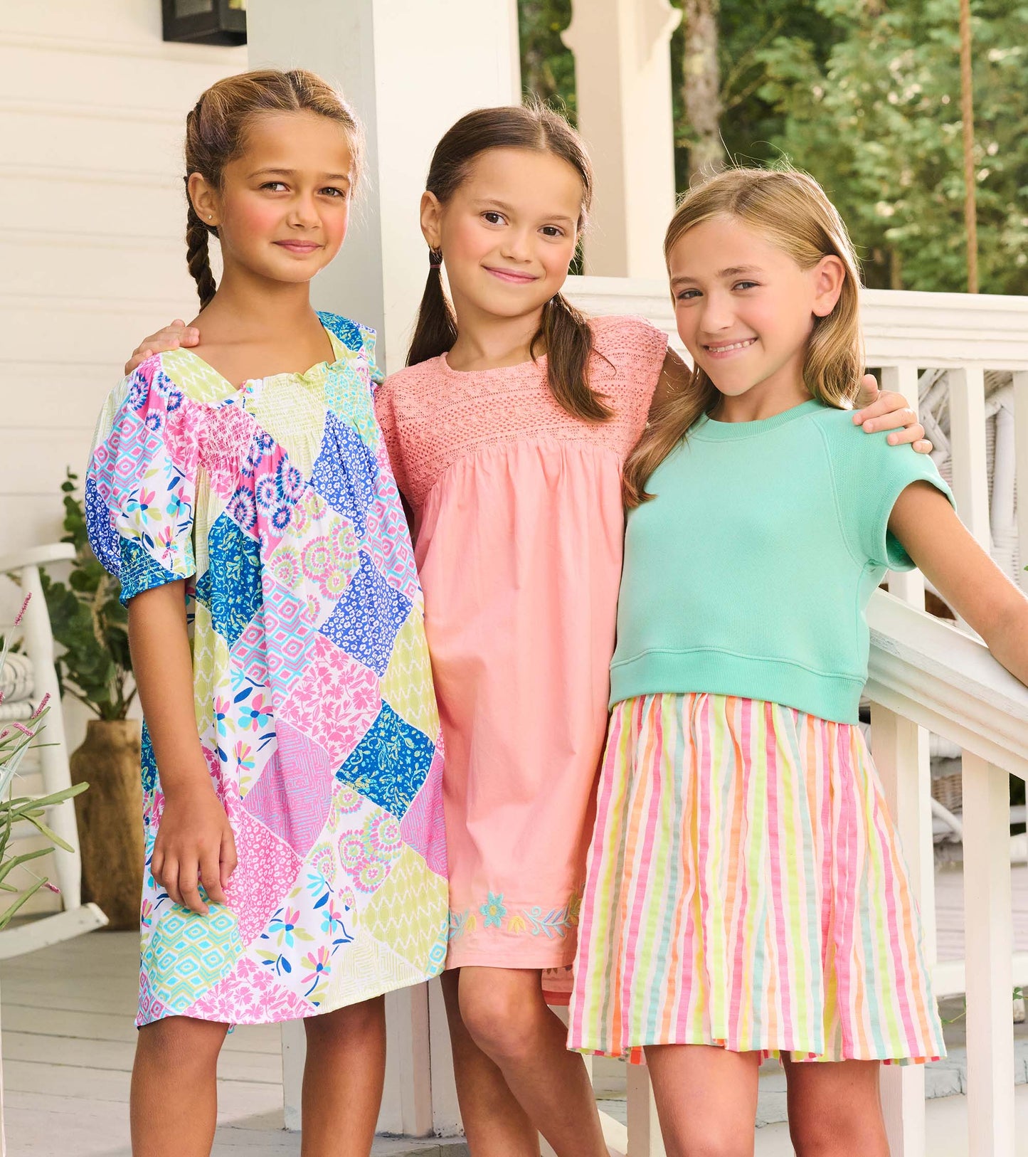 Girls wearing colorful summer dresses, including a patchwork print dress, a pink dress, and a mint top with striped skirt