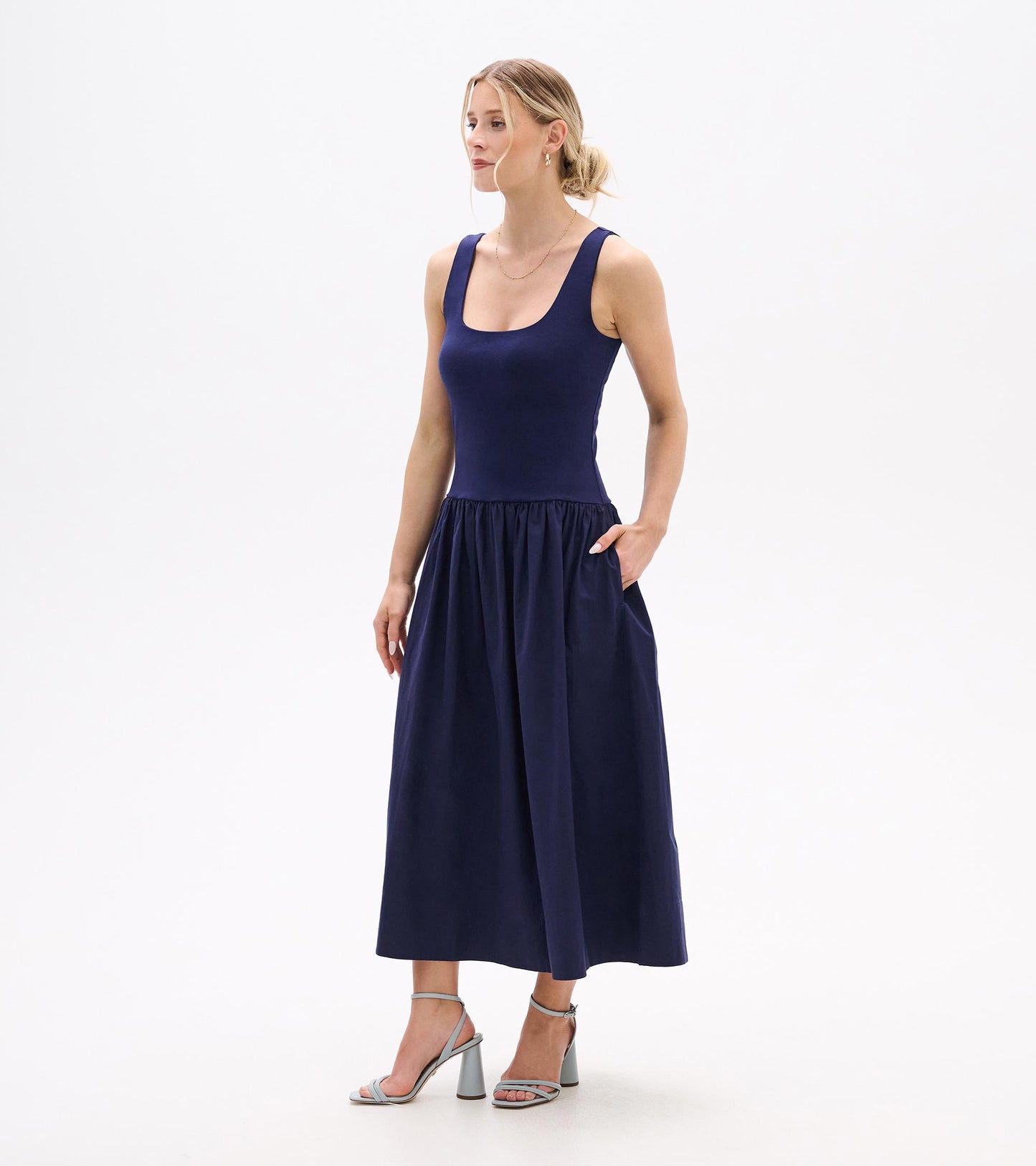 Navy sleeveless midi dress with scoop neckline, fitted bodice, and gathered skirt, shown on model.