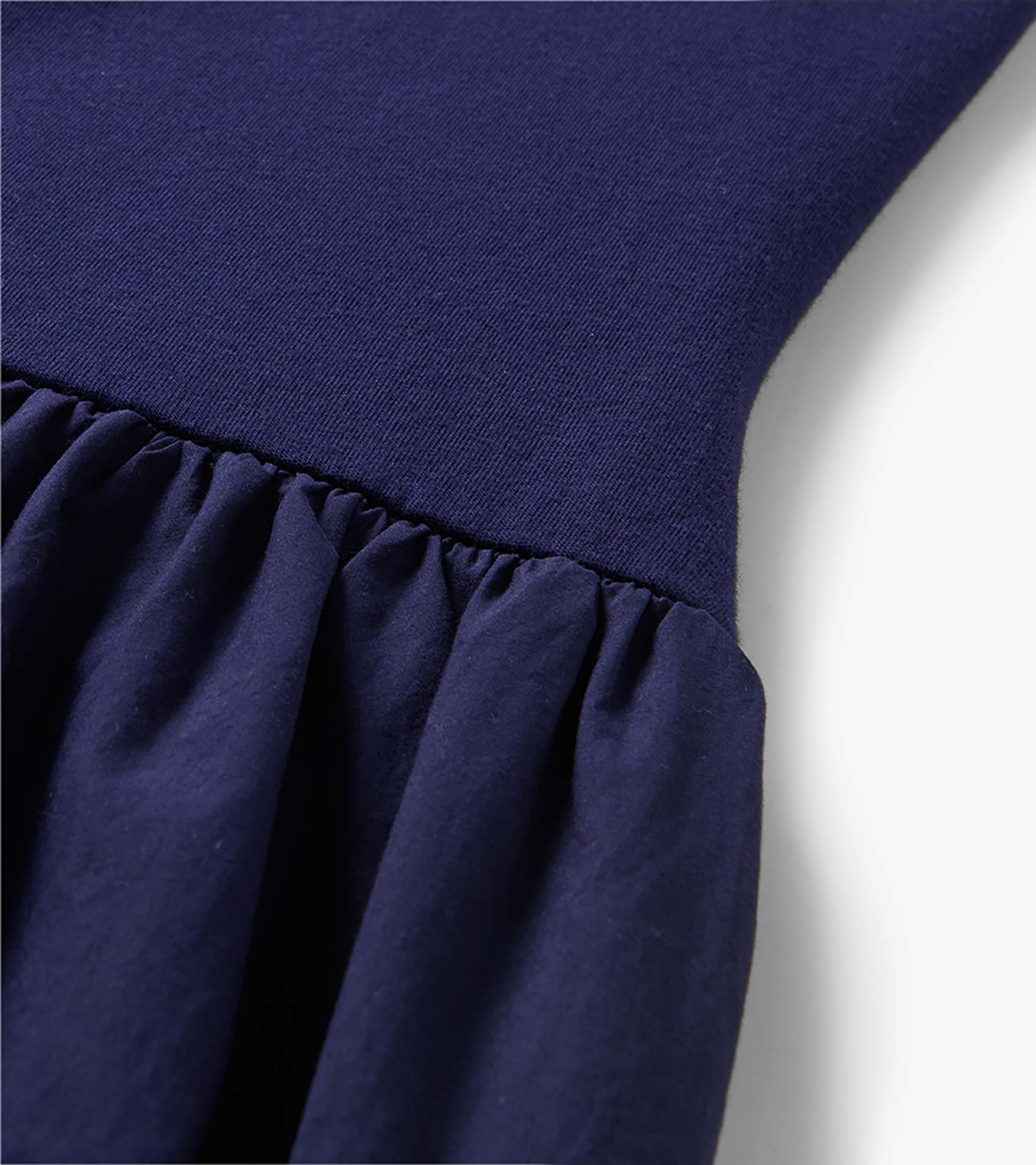 Close-up of a navy blue midi dress with a ribbed knit bodice and gathered skirt seam