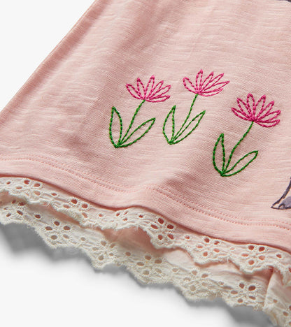 Pink toddler shorts with embroidered flowers and white lace hem, close-up view
