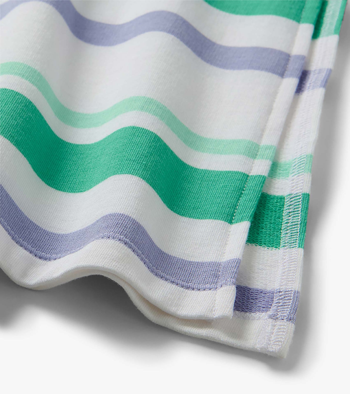Close-up of white midi dress fabric with wavy green and lavender stripes and hem stitching
