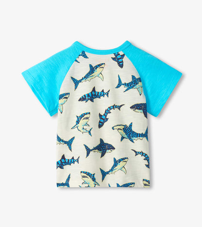 Front view of a boys raglan T-shirt with turquoise sleeves and cream body covered in blue shark print.