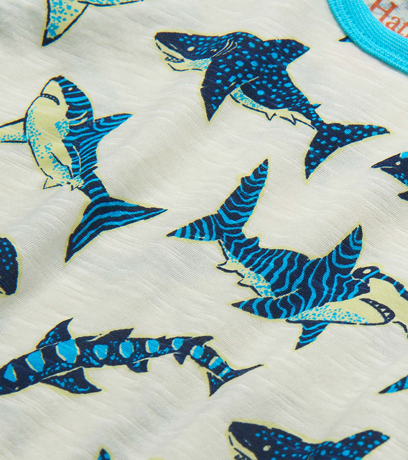 Close-up of white fabric with blue and navy shark print pattern on a toddler T-shirt
