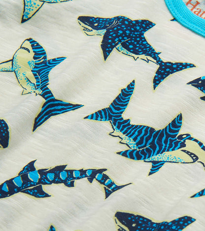 Close-up of white fabric with blue and navy shark print pattern on a toddler T-shirt