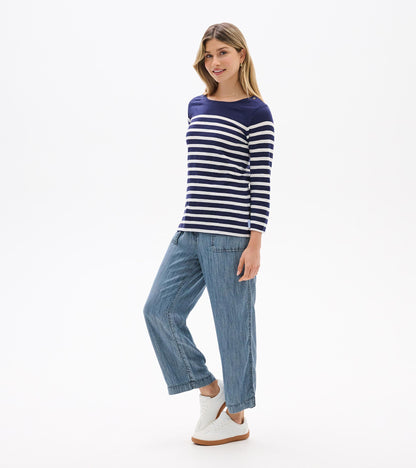 Woman wearing navy and white striped long-sleeve boat-neck top with button detail at shoulder, front view