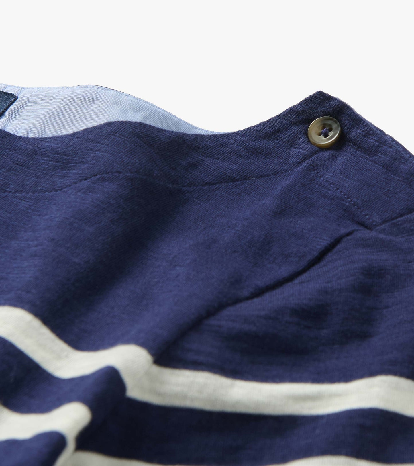 Close-up of navy and white striped knit top with button detail at the shoulder.