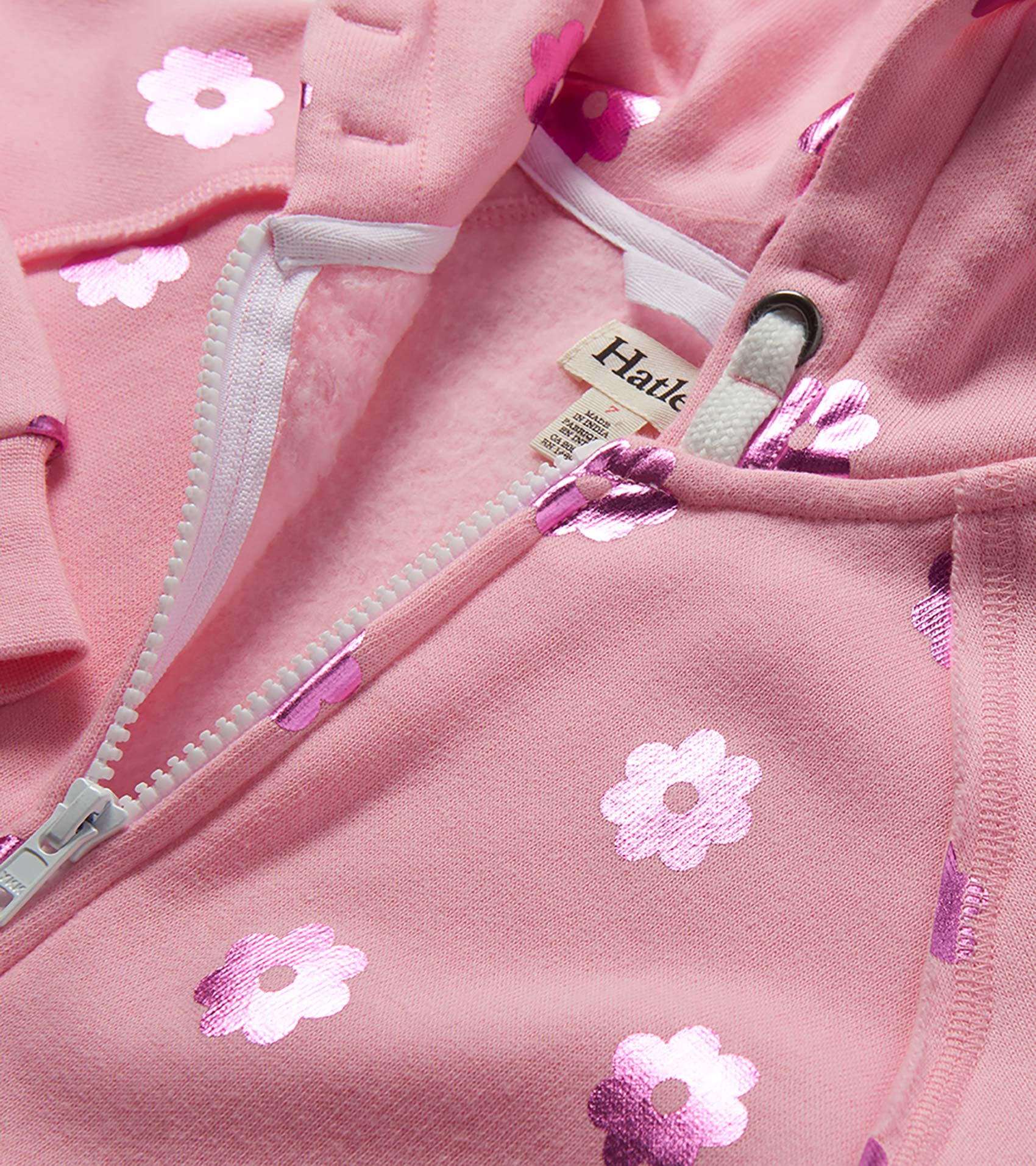 Pink girls zip-up hoodie with white floral print and drawstring hood, close-up view