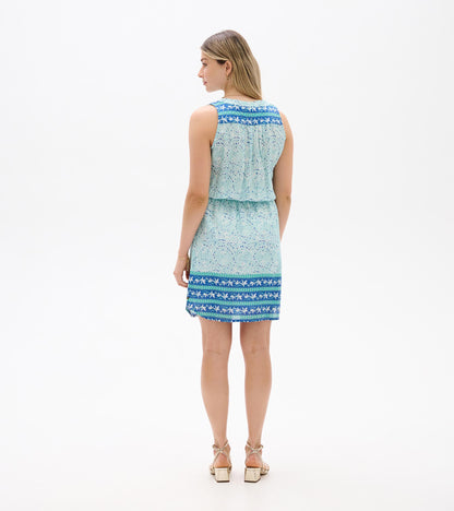 Back view of a sleeveless light blue ikat print dress with blue patterned trim at the shoulders and hem.