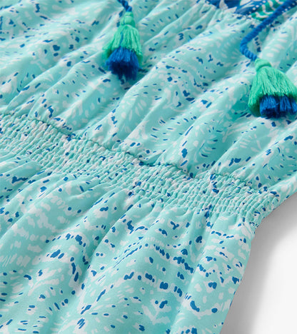 Close-up of a mint and blue ikat-print dress with smocked waist and tassel ties