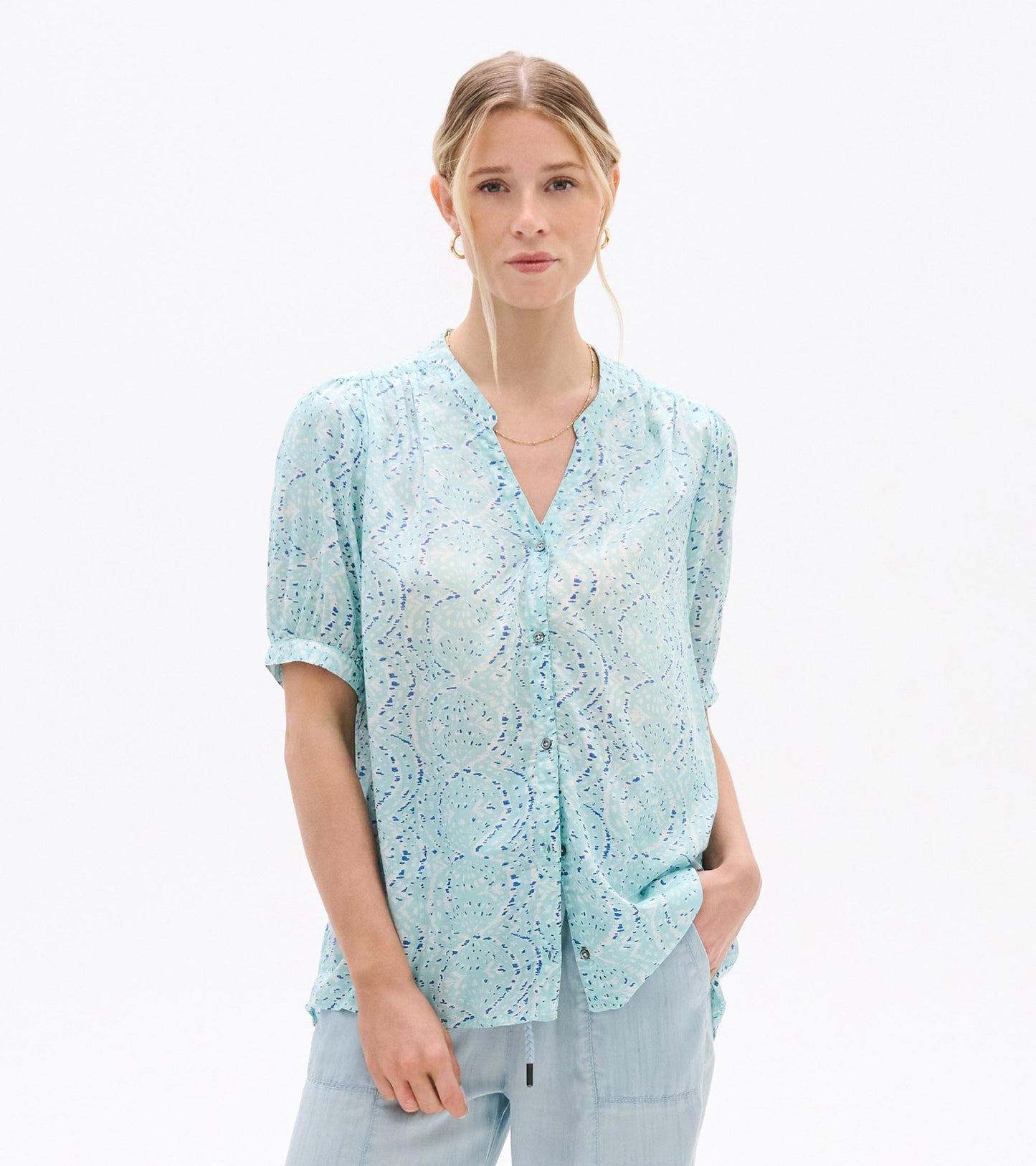 Light blue patterned short-sleeve blouse with V-neck and button front, worn by a model, front view