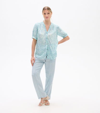 Light blue short-sleeve blouse with ikat print, button front and V-neck, worn on a model