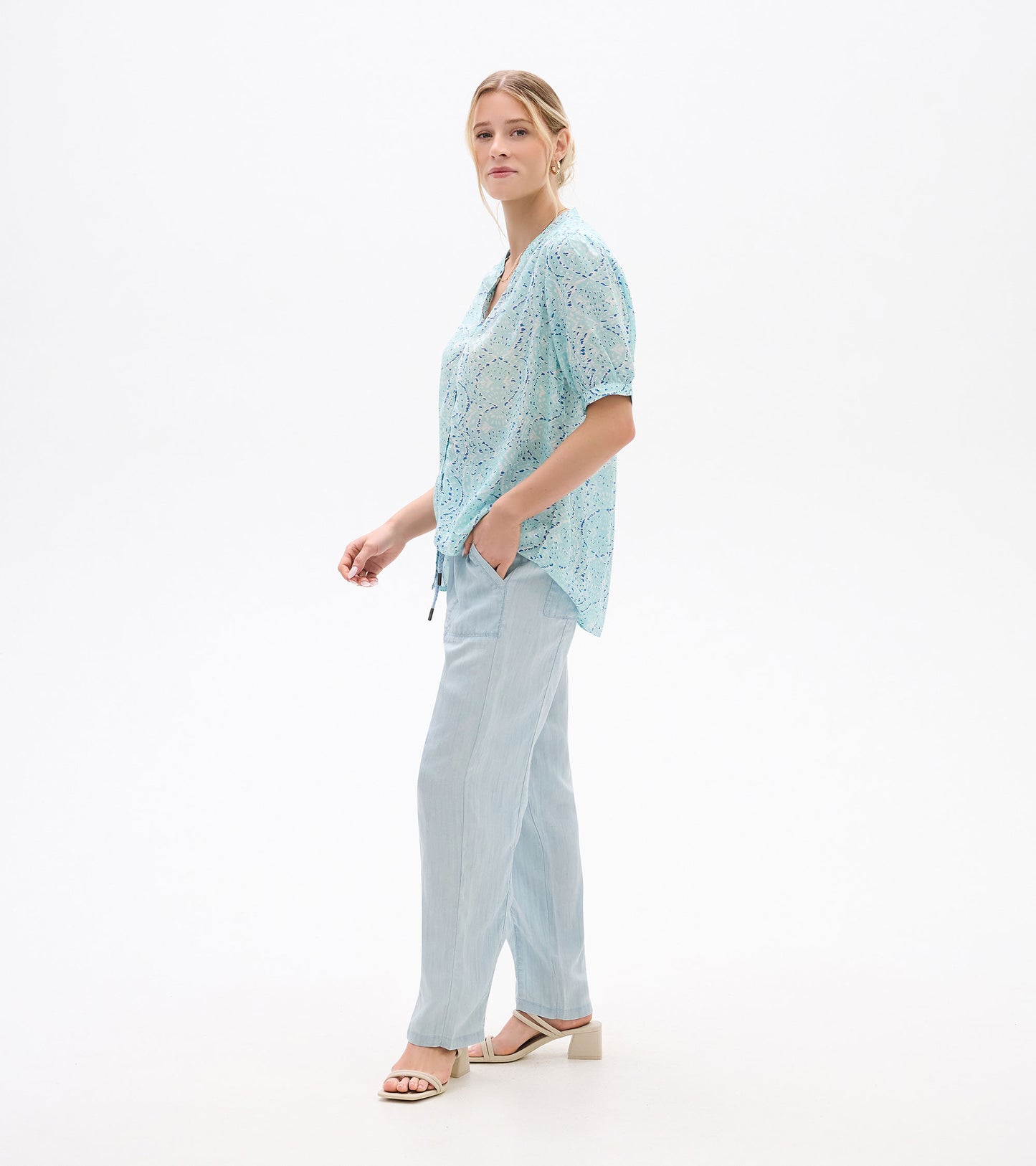Light blue patterned short-sleeve blouse with V-neck and tie hem, shown on model in side view