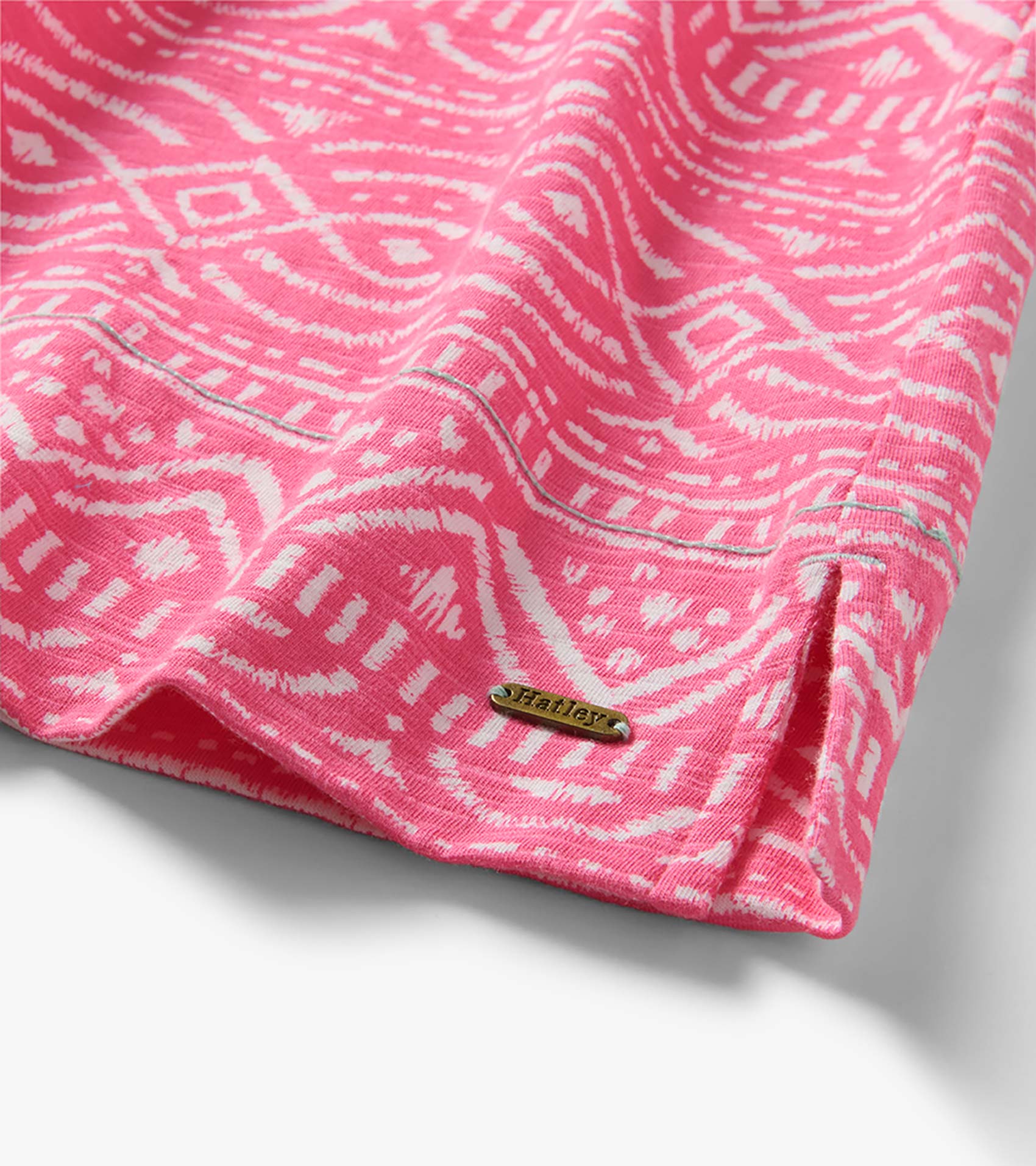 Pink and white patterned knit dress hem with side slit and small metal logo plaque