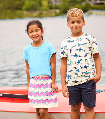 Girls pink, cream, and blue striped crochet skirt with scalloped hem, worn by a child outdoors