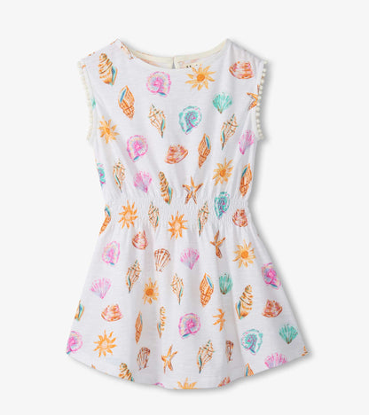 Sleeveless white girls dress with colorful seashell and sun print, smocked waist, and flared skirt