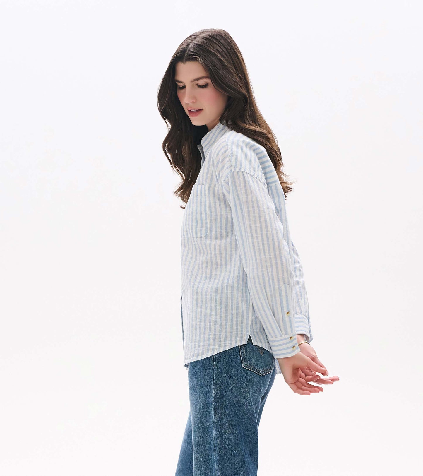 Side view of relaxed blue and white striped button-down shirt with chest pocket and curved hem