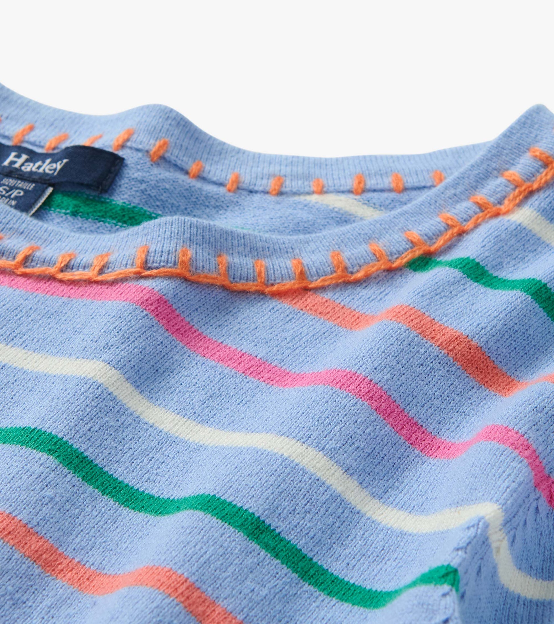 Close-up of a light blue knit top with multicolor wavy stripes and orange contrast stitching at the neckline.