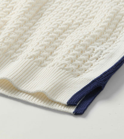 Close-up of a white knit tank top with textured cable pattern and navy trim at the hem