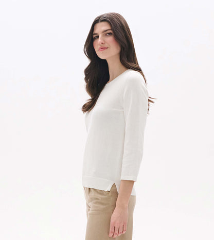 White knit top with 3/4 sleeves, crew neckline, and side slit hem, shown on a model from the side.