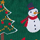 Snowman in Santa hat and red scarf beside decorated Christmas tree