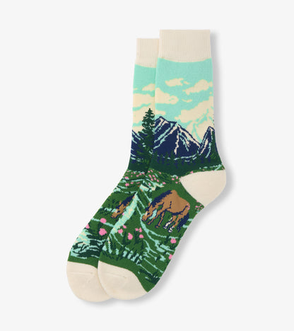Pair of cream crew socks with mountain, forest, and horse landscape pattern in blue, green, and pink.