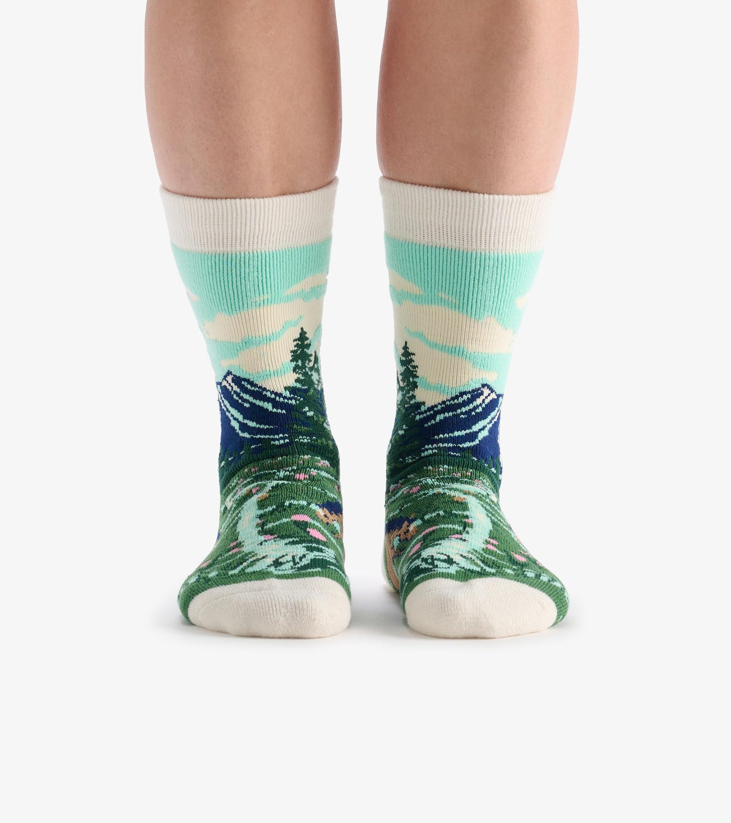 Knee-high cozy socks with mountain and forest landscape pattern in teal, green, navy, and cream