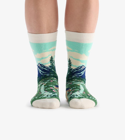 Knee-high cozy socks with mountain and forest landscape pattern in teal, green, navy, and cream