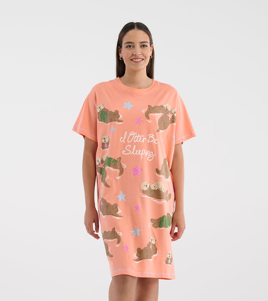 Model wearing a coral pink short-sleeve sleepshirt with otters, starfish, and 'I Otter Be Sleeping' text