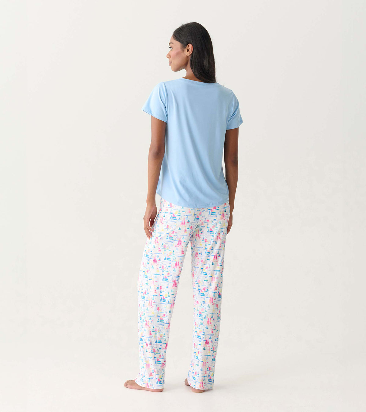 Women's placid blue V-neck T-shirt back view on model with white sailboat print pajama pants