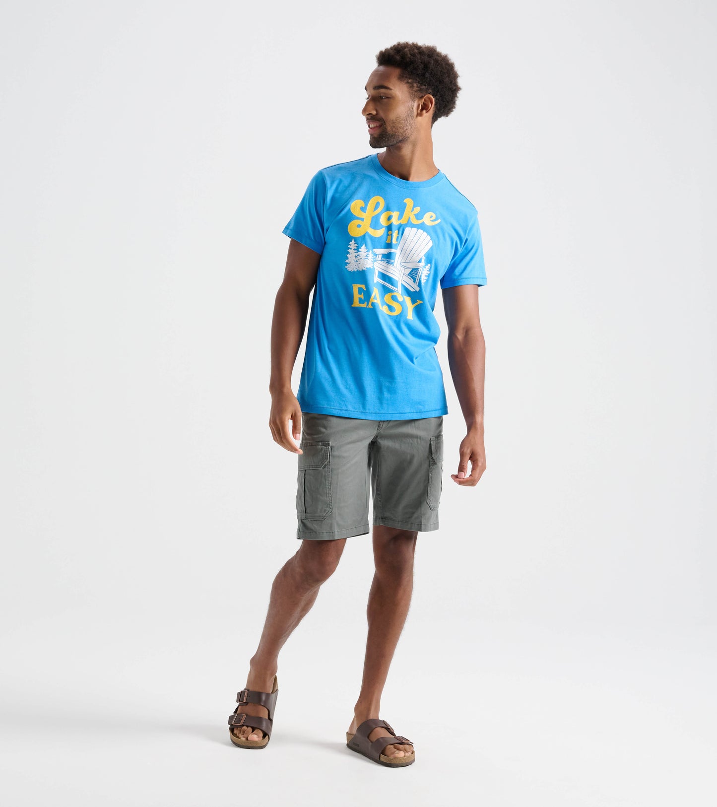Model wearing blue Lake It Easy graphic tee with gray shorts and brown sandals