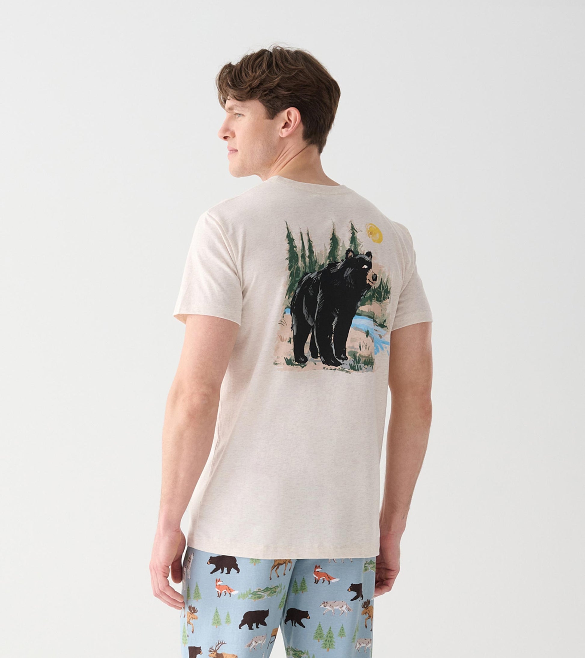 Back view of oatmeal crew neck T-shirt with black bear, trees, blue stream and yellow sun graphic