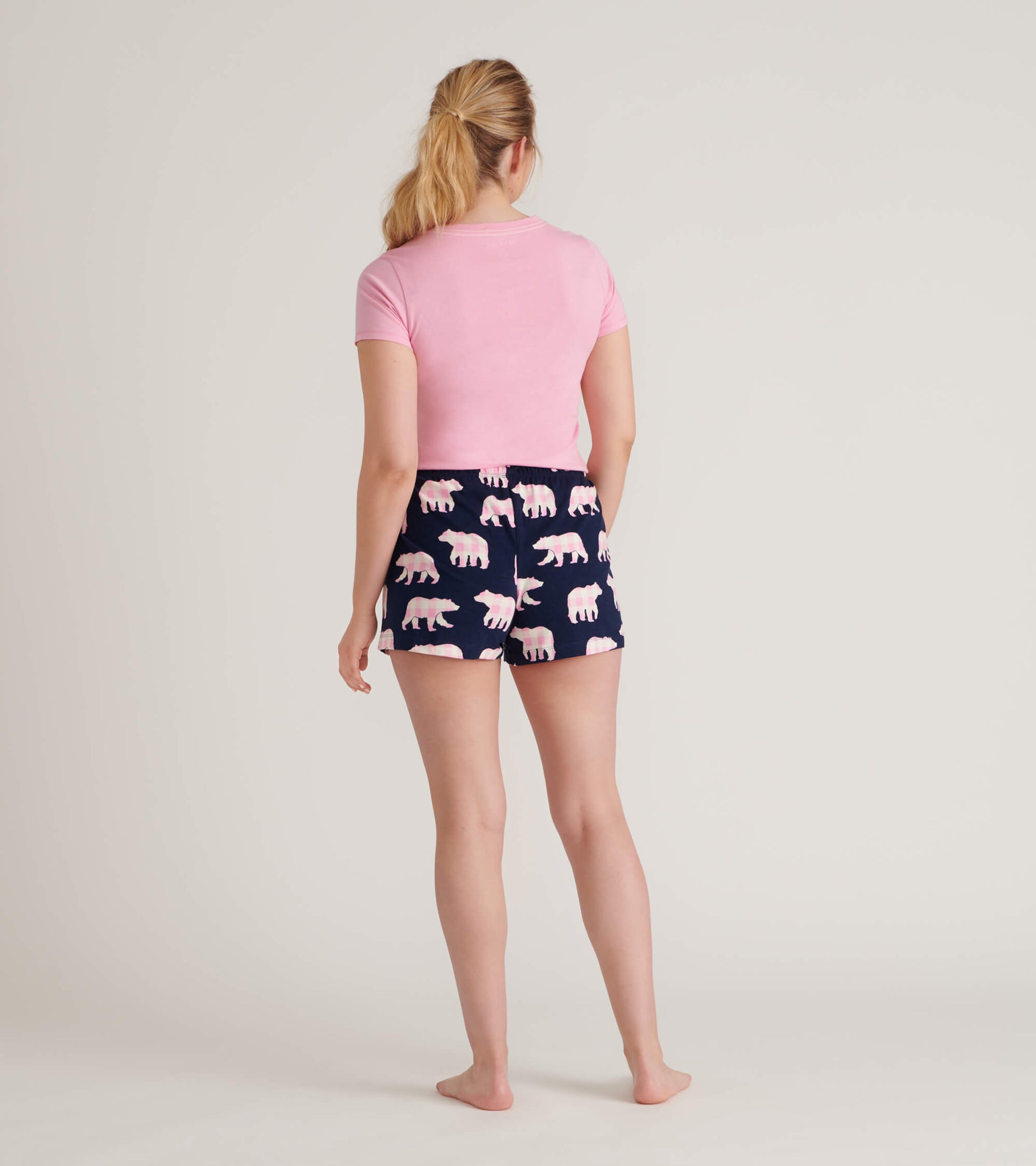 Back view of a pink short-sleeve pajama T-shirt with navy bear-print shorts on a model