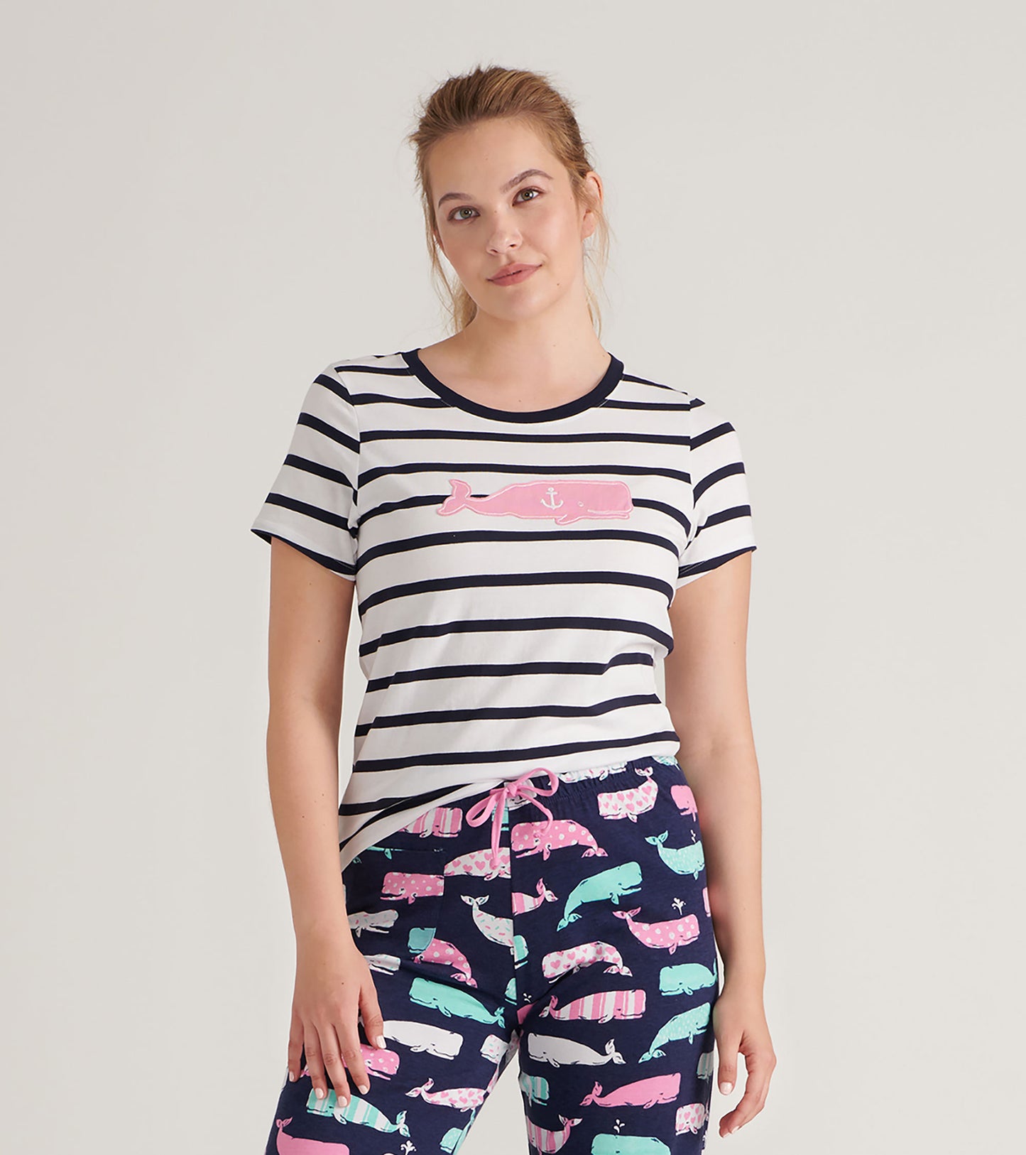 Striped women's pajama tee featuring a pink whale graphic, paired with colorful whale-patterned pants.