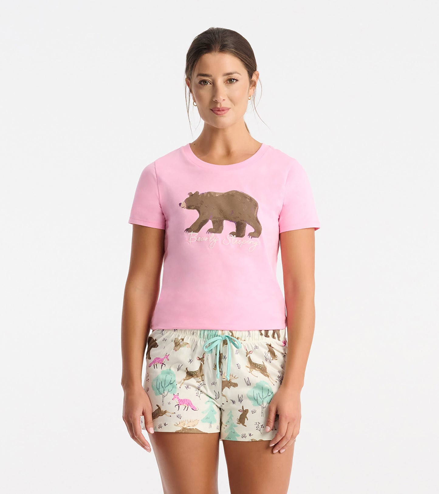 Pink short-sleeve pajama T-shirt with bear graphic and text, paired with printed pajama shorts on a model.