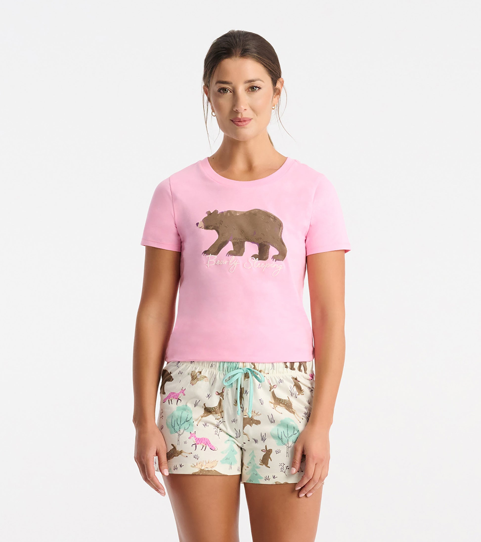 Pink short-sleeve pajama T-shirt with bear graphic and text, paired with printed pajama shorts on a model.