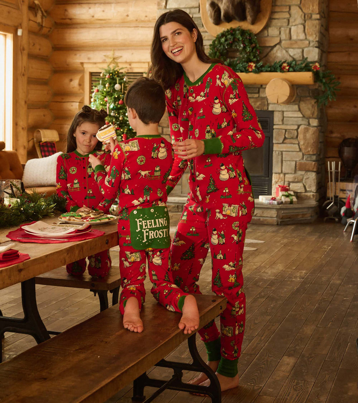 Kids and woman in matching red Christmas onesies in a cabin, showing the back flap seat detail