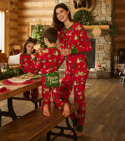Kids and woman in matching red Christmas onesies in a cabin, showing the back flap seat detail