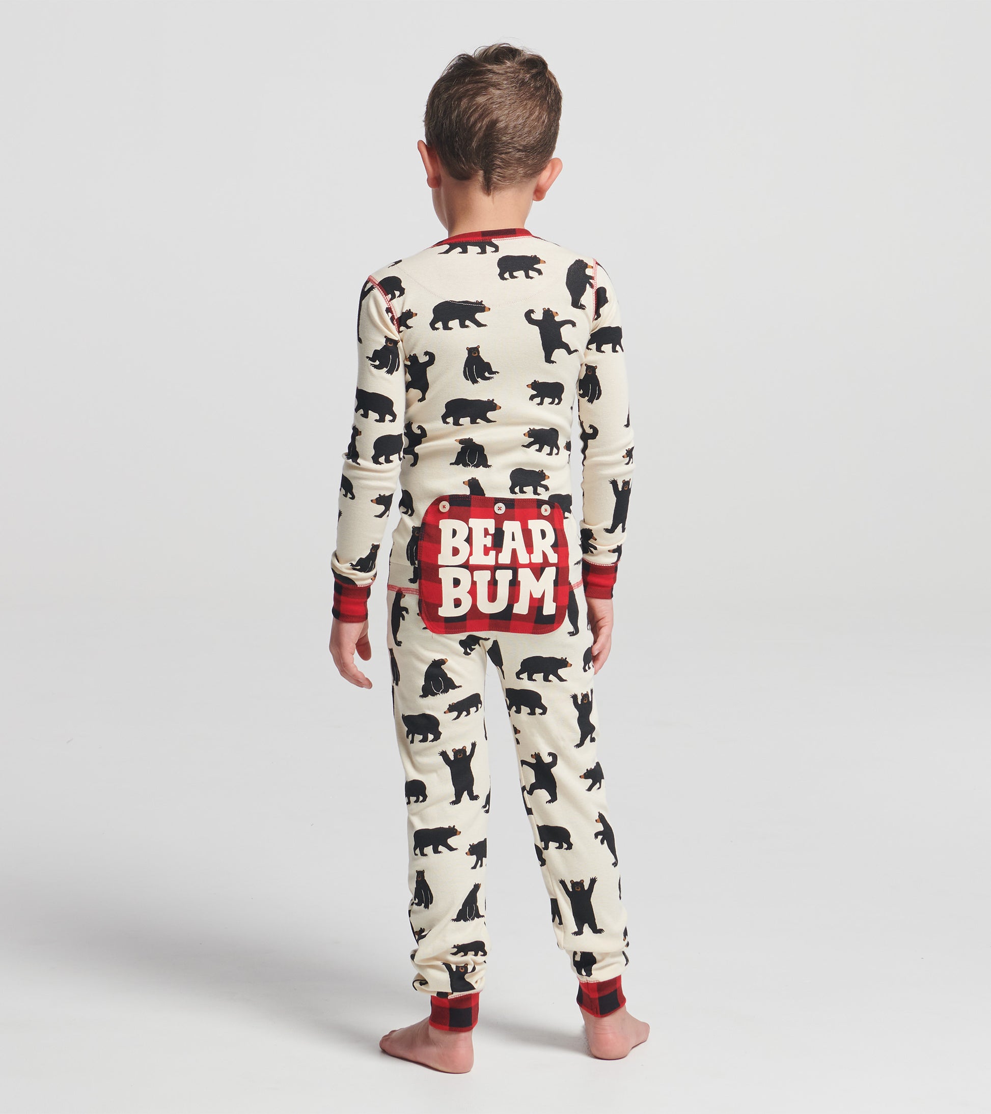 Cream-colored kids' onesie with black bear prints and a red plaid "BEAR BUM" design on the back.